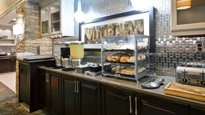 Una barra de desayuno con detalles de pared de piedra, una estación de café y una exhibición de pasteles.