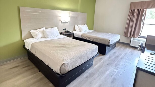 A hotel room with two beds, a desk, and a window with curtains. - Quality Inn & Suites Thomasville-High Point (Thomasville)