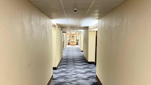 A hotel hallway with a patterned carpet, cream-colored walls, and a security camera on the ceiling. - Quality Inn & Suites Thomasville-High Point (Thomasville)