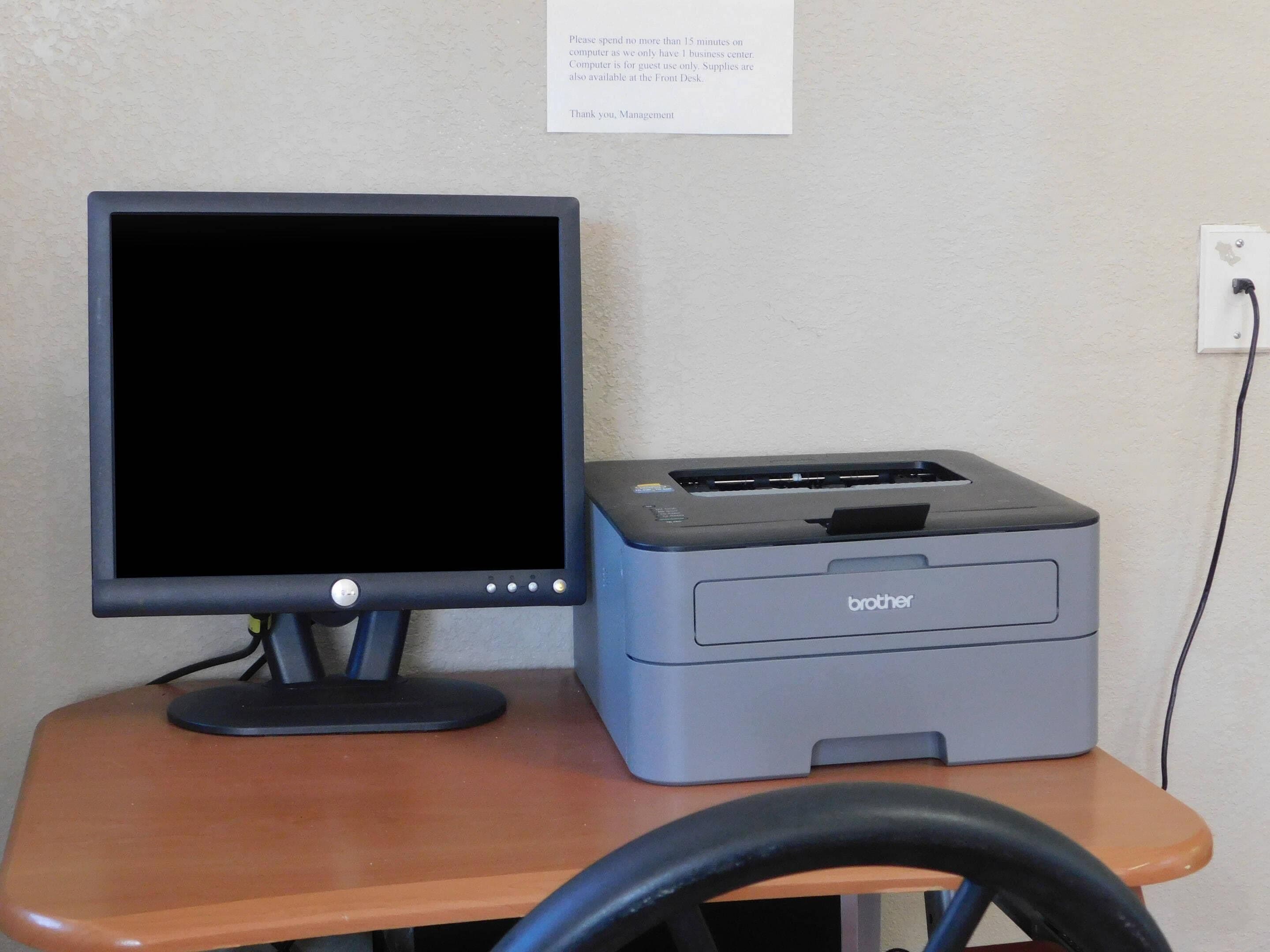 A computer monitor and a Brother printer on a wooden desk.