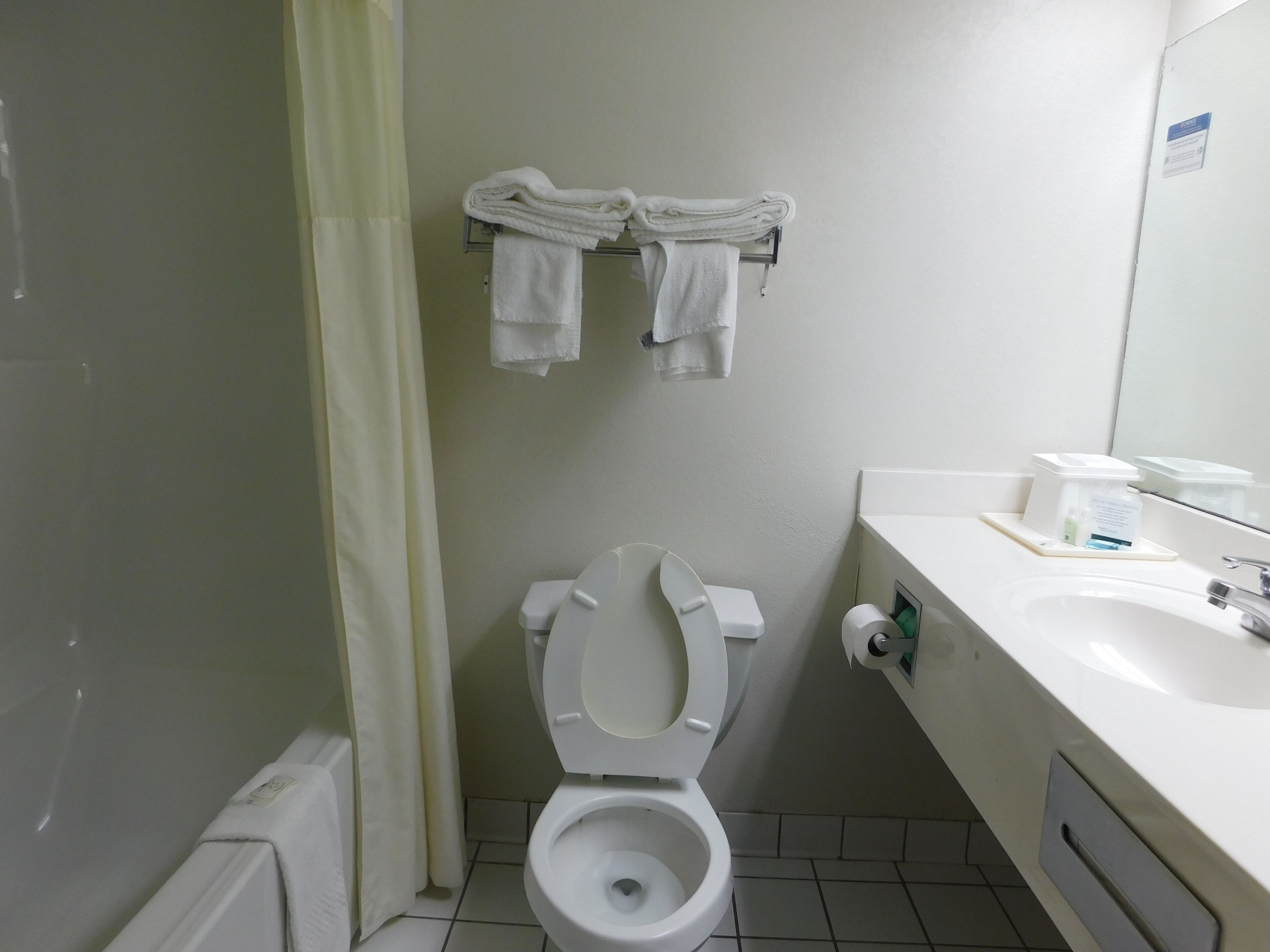 Un baño pequeño con inodoro, lavamanos y toallero con toallas dobladas.