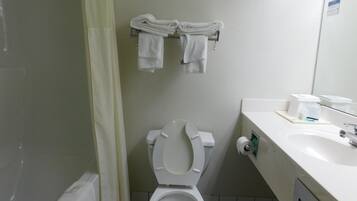 Un baño pequeño con inodoro, lavamanos y toallero con toallas dobladas.