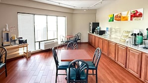 A spacious room with a wooden floor, a dining table with chairs, a kitchenette with a refrigerator, and a large window with blinds. - Quality Inn & Suites Thomasville-High Point (Thomasville)