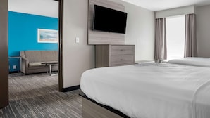 Una habitación de hotel con una cama grande, un televisor de pantalla plana en la pared, un sofá y una mesita.