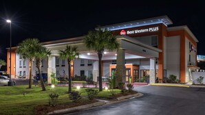 Un hotel Best Western PLUS con área de estacionamiento techada, palmeras y una entrada bien iluminada.