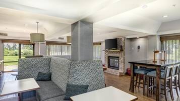 Un interior moderno con un sofá modular, una chimenea, un comedor y un televisor.