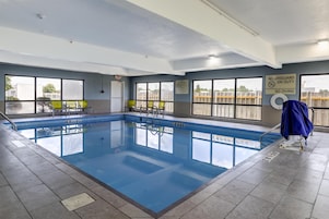 An indoor swimming pool with clear water, a lifeguard chair, and a sign indicating no lifeguard on duty.