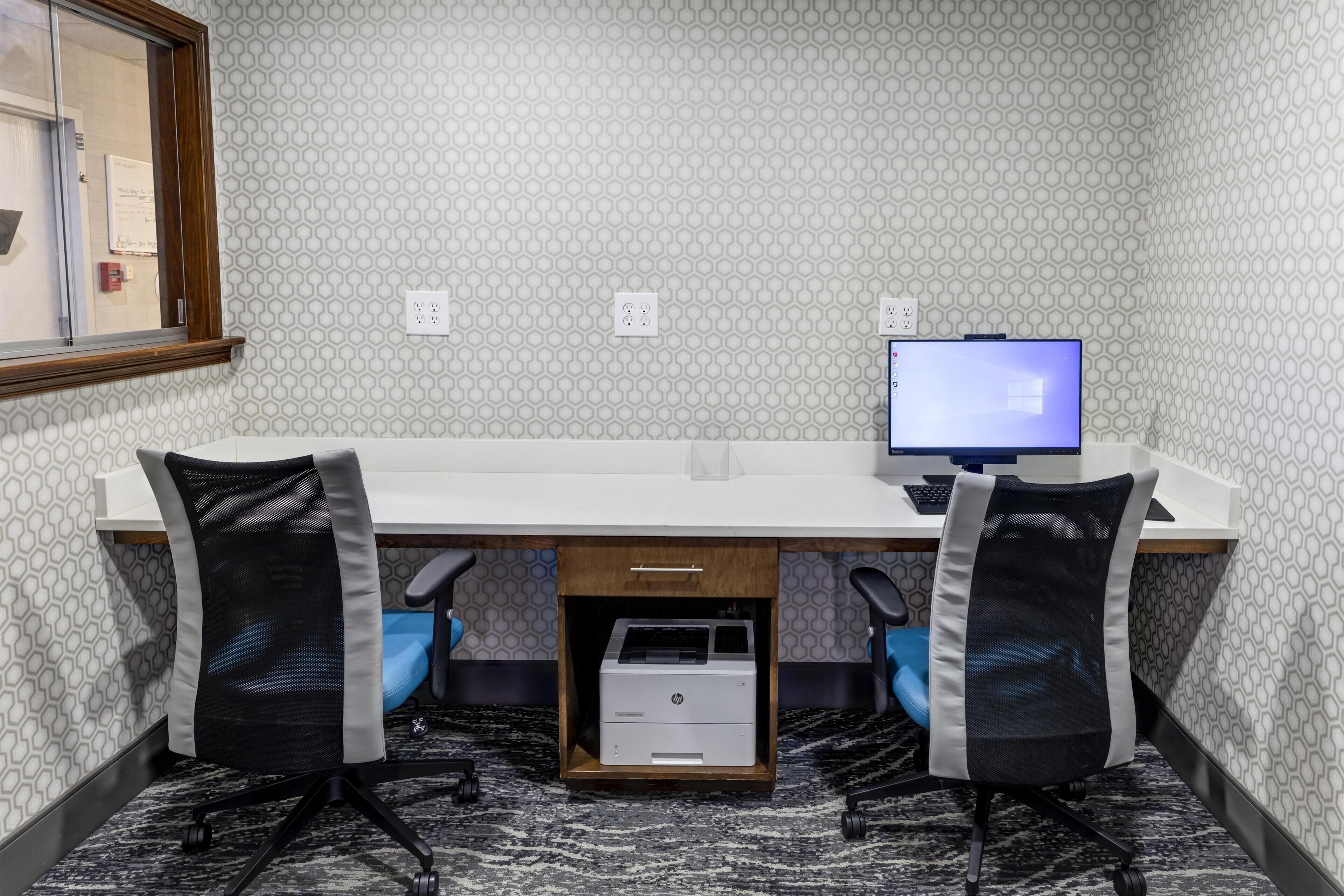 A modern office space with a white desk, two office chairs, a computer monitor, and an HP printer.