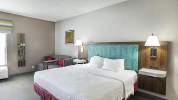 Ein Hotelzimmer mit einem großen Bett, einem Schlafsofa, einem kleinen Tisch, einer Wandlampe und einem Bild.