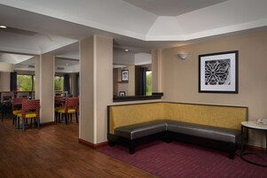 Um saguão de hotel com área de estar, mesas e cadeiras.