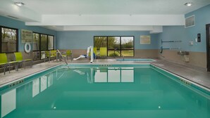 A swimming pool with clear water, green chairs, and a lifeguard stand. - Hampton Inn Shelbyville (Shelbyville)