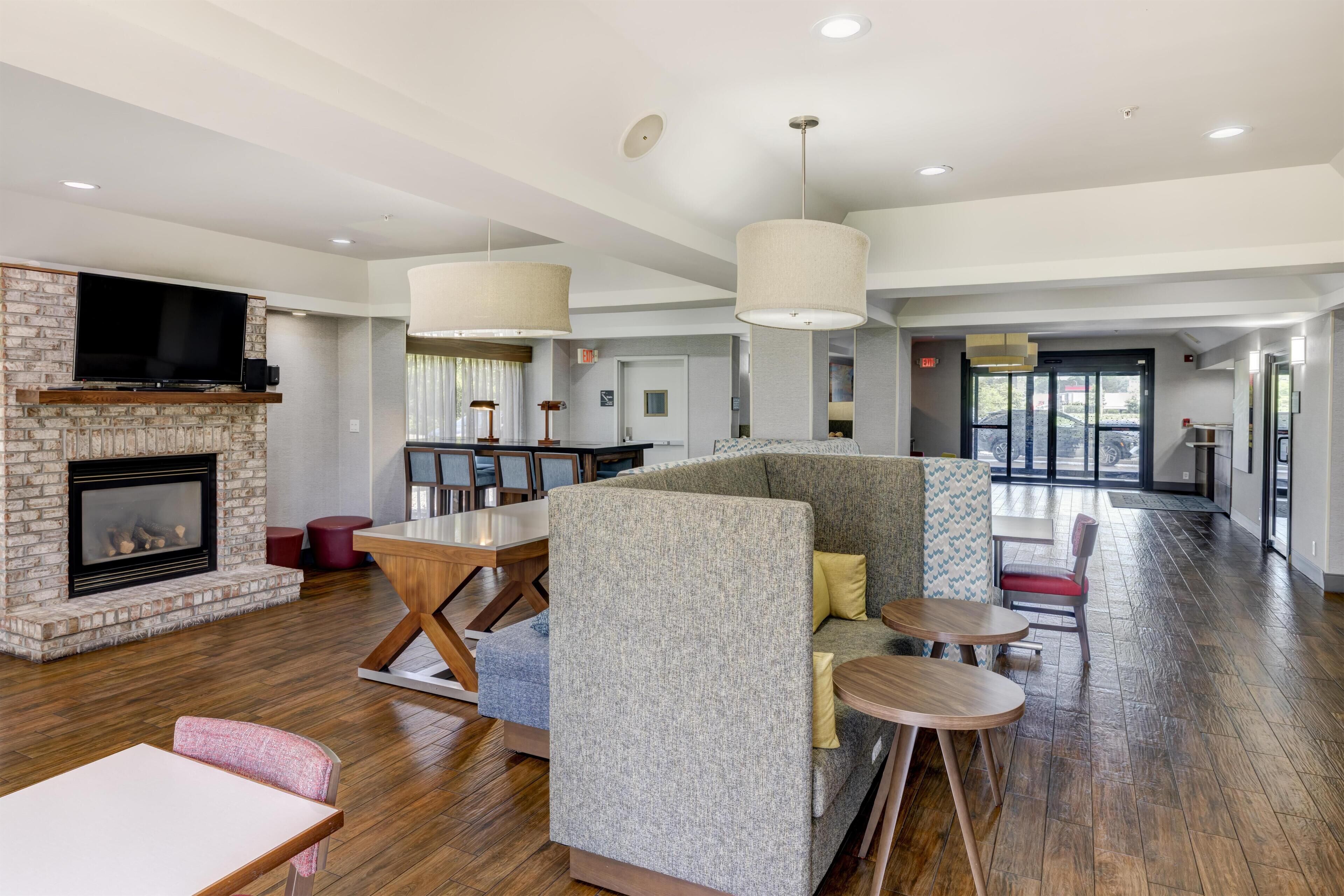 A spacious lobby with a fireplace, seating areas, and a television mounted on a brick wall.