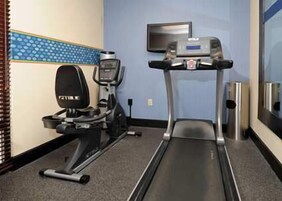 Un gimnasio con cinta de correr, elíptica y bicicleta estática.