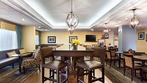 A hotel dining area with a large round table, multiple chairs, and a chandelier. - Hampton Inn Morganton (Morganton)