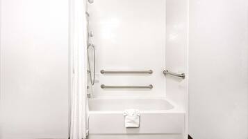 A white bathtub with a showerhead, grab bars, and a towel hanging on the side.