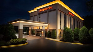 A Hampton Inn hotel with a well-lit entrance, a covered outdoor seating area, and neatly trimmed bushes. - Hampton Inn Morganton (Morganton)