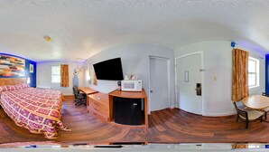 Een slaapkamer met een bed, bureau, stoel en een televisie.