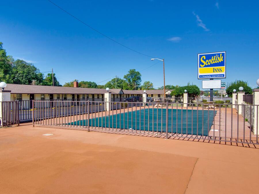 A motel with a swimming pool, fenced area, and a sign for Scottish Inns.