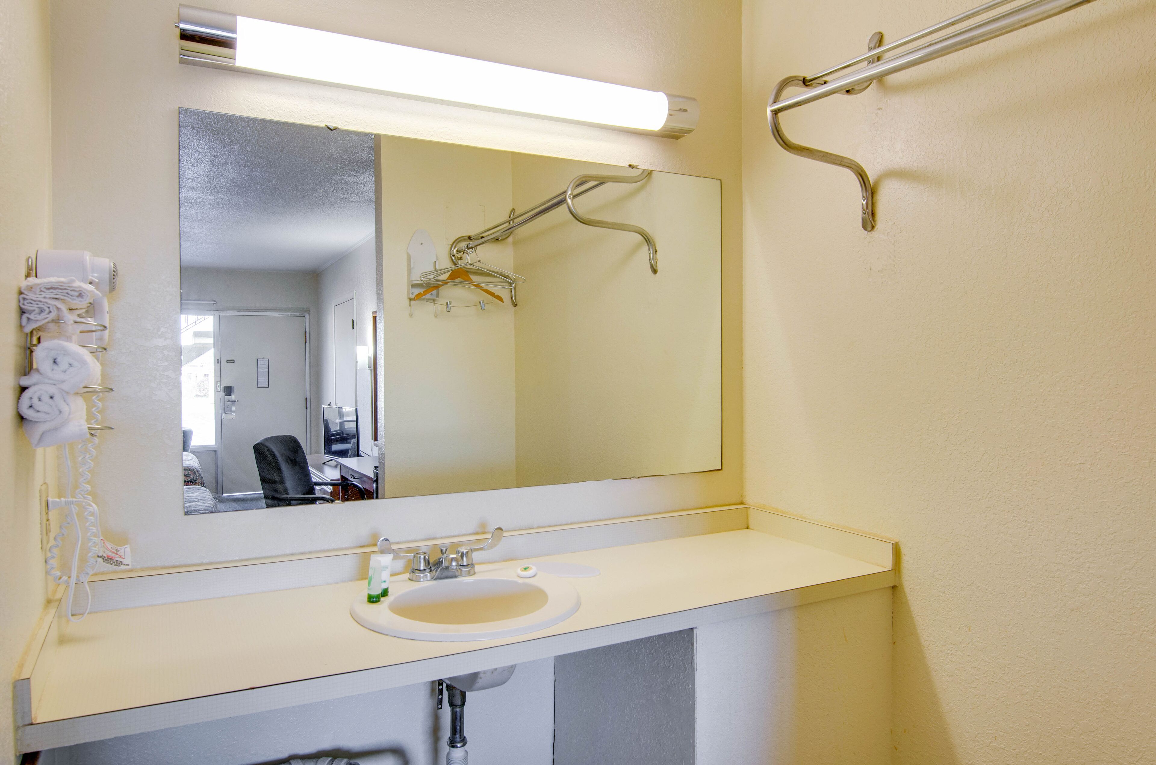 A bathroom with a white sink, mirror, and towel rack.