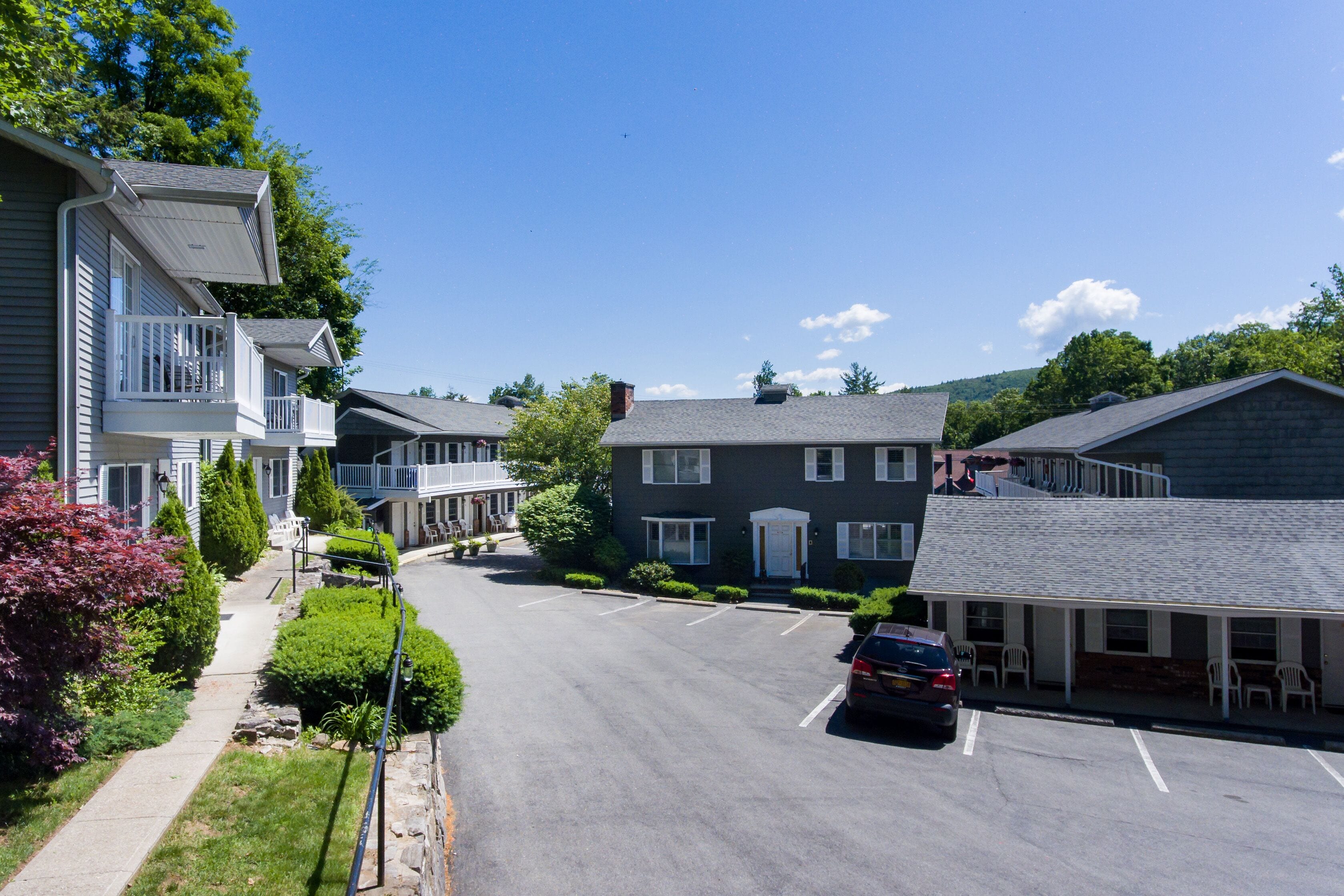 Une rue résidentielle bordée de maisons, avec un parking et une voiture.