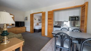 Une chambre d’hôtel compacte comprenant un coin cuisine, un espace repas, un lit et un téléviseur.