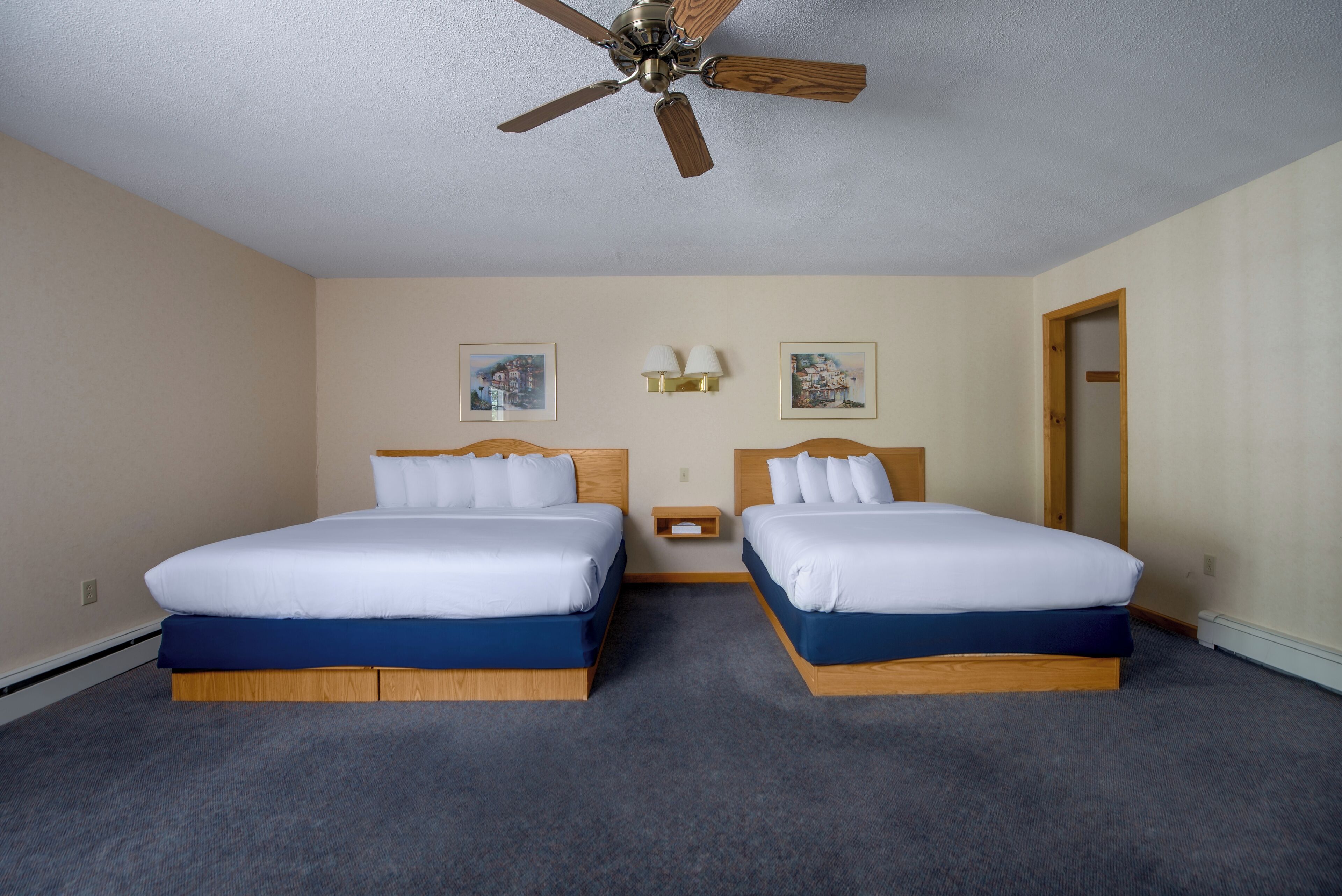 Ein Hotelzimmer mit zwei Betten, einem Deckenventilator und zwei Wandleuchten.
