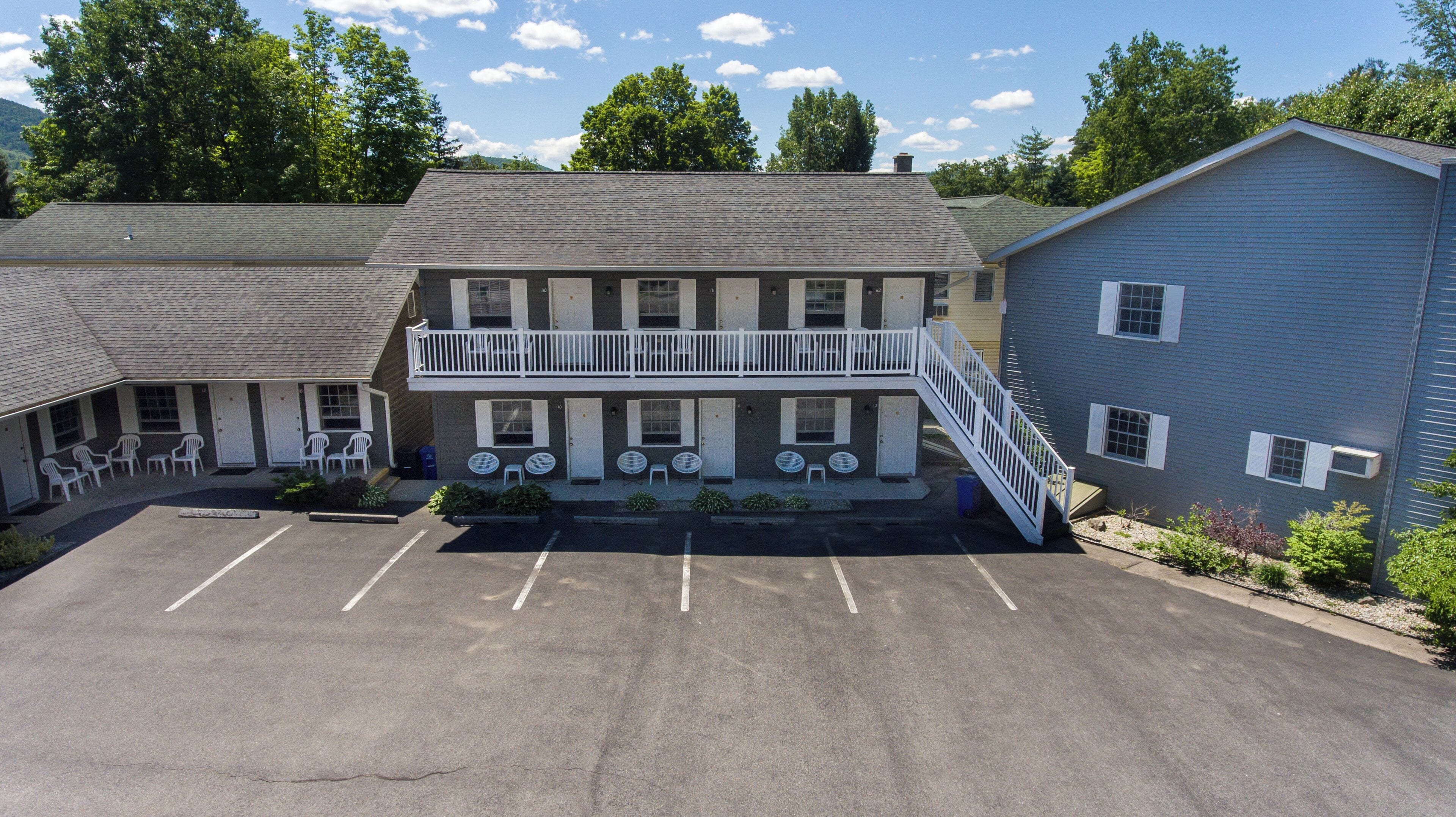 A two-story motel with a balcony, outdoor seating, and a parking lot.