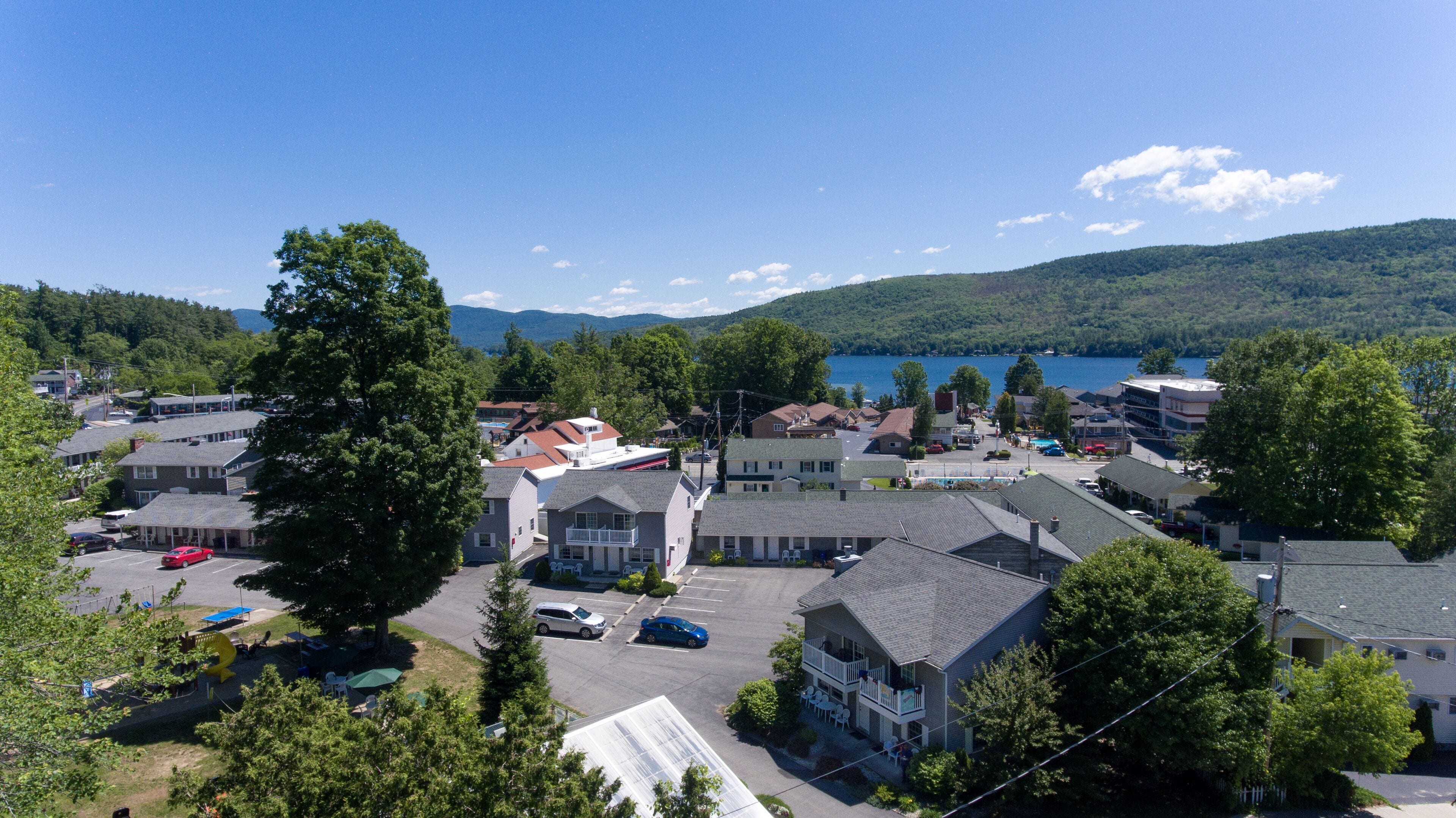 Une ville située au bord d’un lac, où se côtoient des immeubles résidentiels et des bâtiments commerciaux, dont un hôtel remarquable doté d’un balcon et offrant une vue sur le lac.