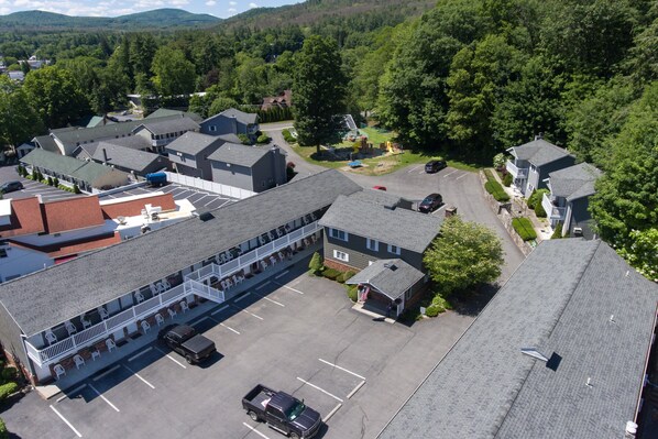Un hôtel à plusieurs étages doté d’un parking, entouré de verdure et de collines.