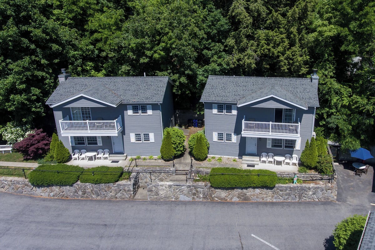 A twin house with a stone retaining wall, a stone staircase, and a patio with outdoor seating.