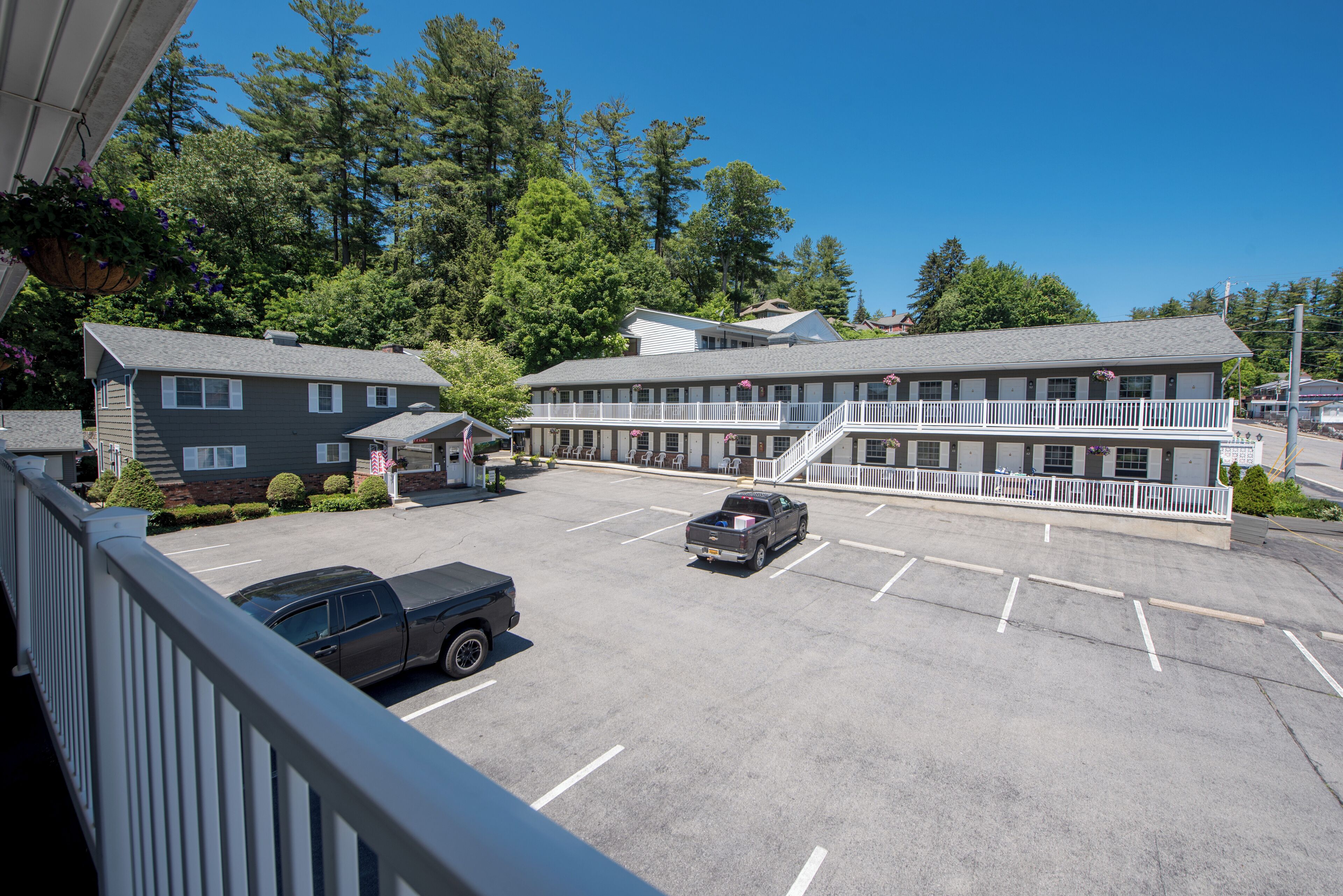 A motel with a parking lot, a covered walkway, and a truck parked in the lot.