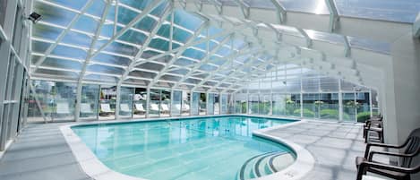 Alberca techada, alberca al aire libre y sombrillas en la alberca