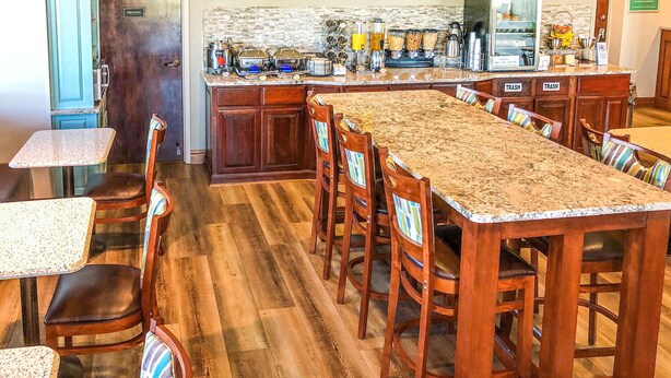 A spacious kitchen with a long dining table, wooden chairs, and a variety of kitchen appliances and utensils. - Best Western Home Place Inn (Camden)