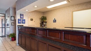 A reception area with a counter, framed awards, a plant, and a sign indicating 'Best Western'. - Best Western Home Place Inn (Camden)