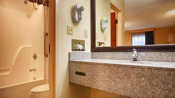 A bathroom with a granite countertop, a sink, a mirror, and a shower.