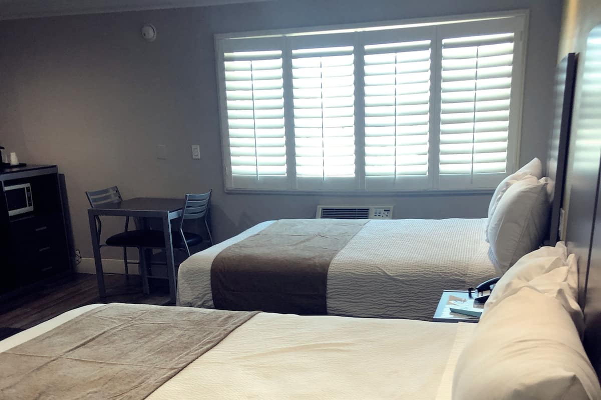 A hotel room with two beds, a desk, and a chair.