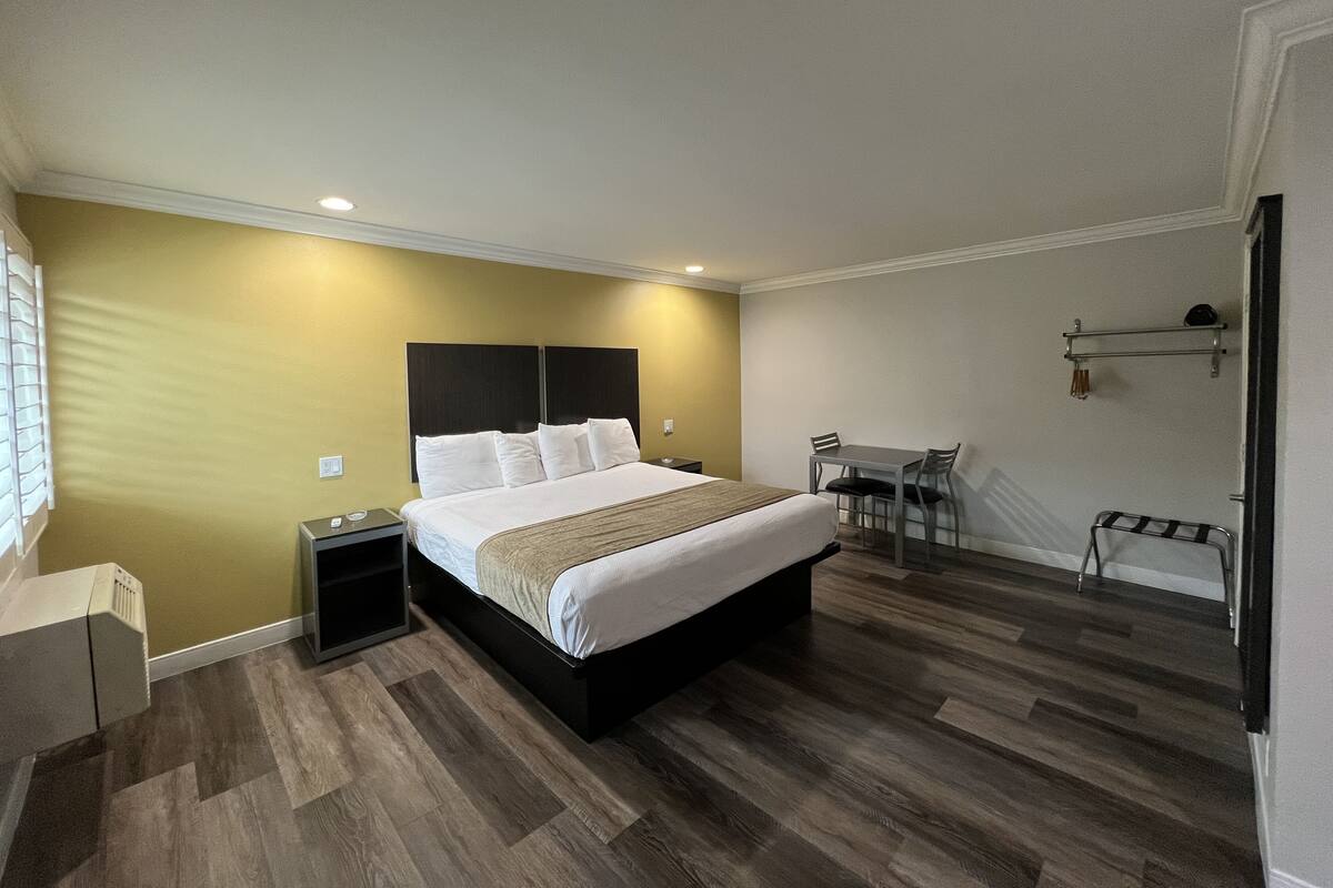 A hotel room with a bed, bedside tables, a desk, and chairs.