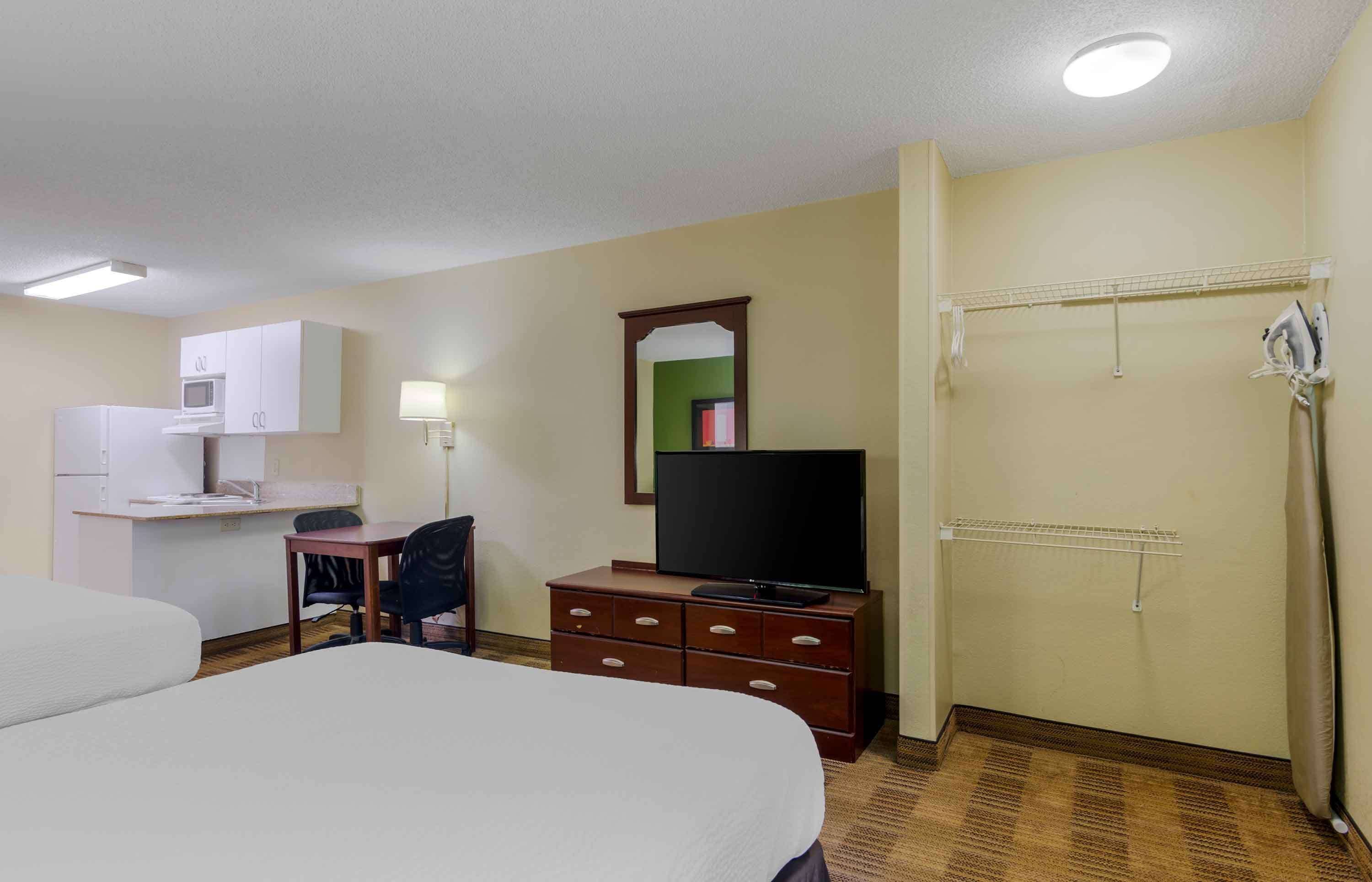 A hotel room with a bed, a desk with a computer, a television, and a wardrobe.