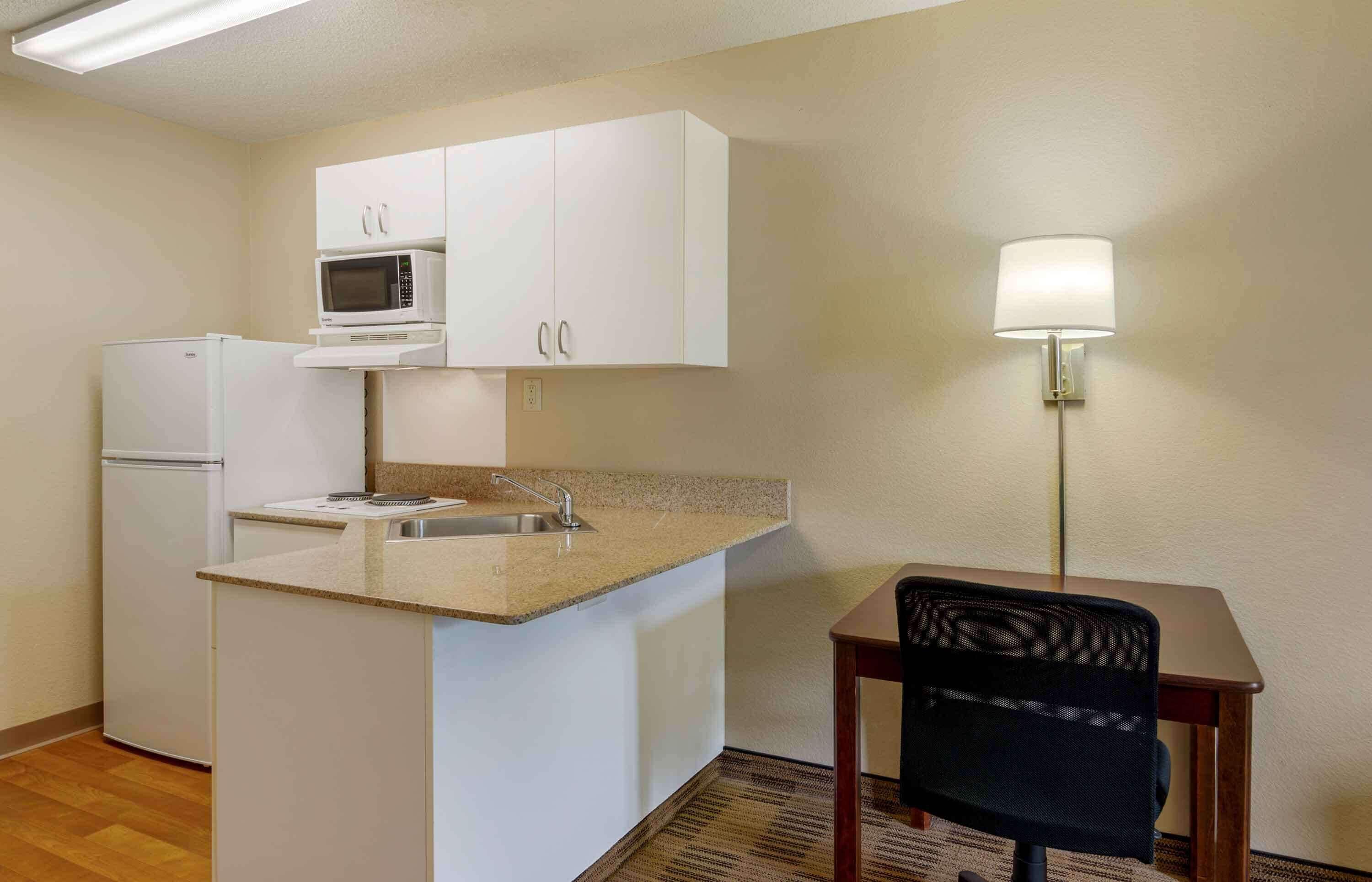 A compact kitchenette with a microwave, refrigerator, and sink.