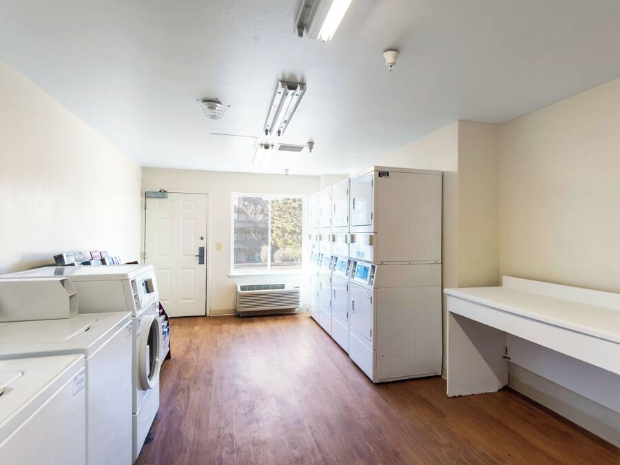 A laundry room with a dryer, washing machine, and a utility room with a water heater and a water meter.