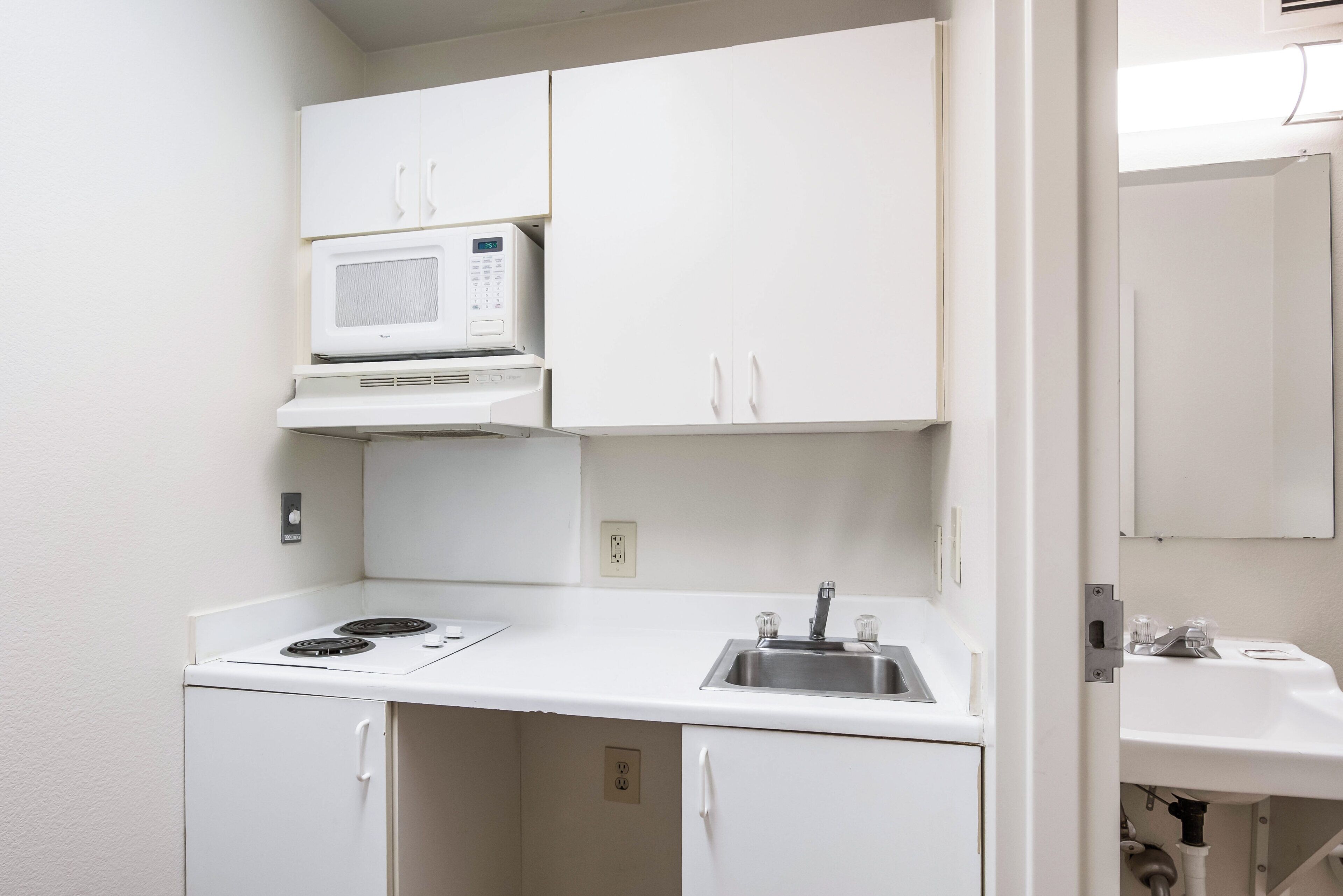 A compact kitchenette with a microwave, stove, and sink.