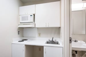 Una kitchenette compacta con microondas, estufa y lavaplatos.