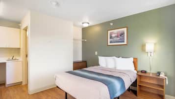 A bedroom with a bed, bedside table, nightstand, and a painting on the wall.