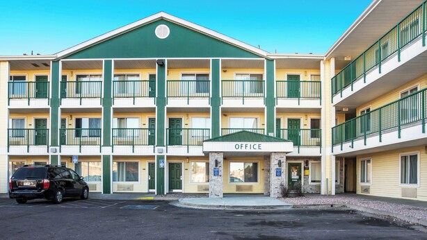 A multi-story building with a green and yellow facade, multiple balconies, and an entrance marked 'OFFICE'. - HomeTowne Studios By Red Roof Colorado Springs - Airport (Colorado Springs)