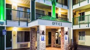 A multi-story building with an 'OFFICE' sign above the entrance, stone pillars, and a green exit sign. - HomeTowne Studios By Red Roof Colorado Springs - Airport (Colorado Springs)