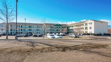 A multi-story motel with a parking lot in front.