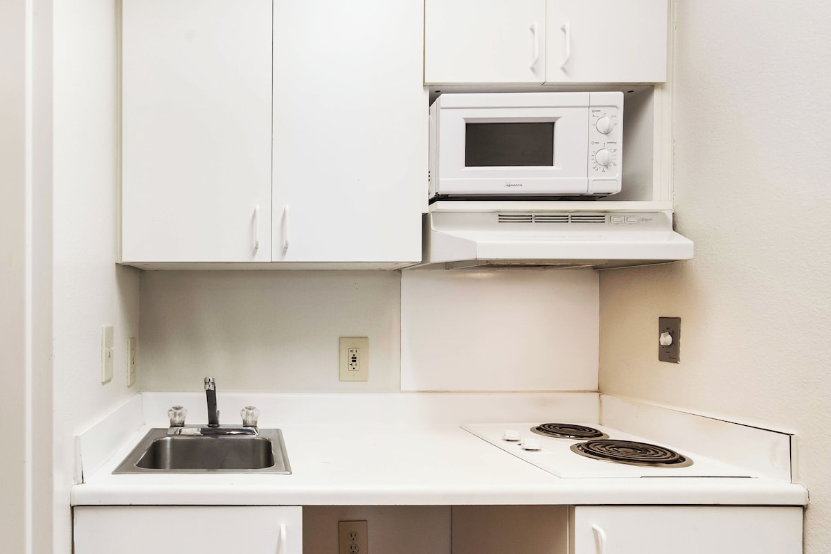 A compact kitchenette with a built-in microwave, a sink, and a stovetop.