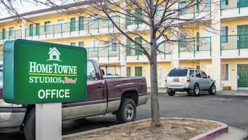 Señalización de HomeTowne Studios Office, con una camioneta estacionada y un edificio al fondo.