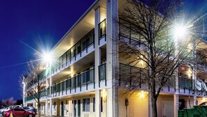 A multi-story hotel with a flat facade, balconies, and a parking area with cars. - HomeTowne Studios By Red Roof Colorado Springs - Airport (Colorado Springs)
