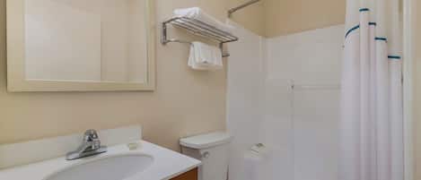 A bathroom with a sink, toilet, and shower area.